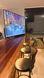 a bar with four chairs and a large screen at Cozy house with pool in Campo Grande