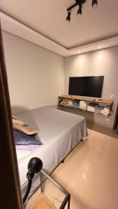 a bedroom with a bed and a flat screen tv at Cozy house with pool in Campo Grande +12 photos