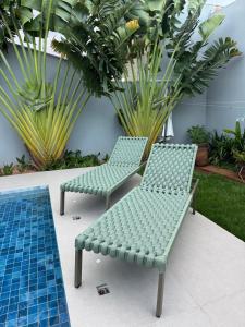 two green chairs sitting next to a pool at Cozy house with pool in Campo Grande