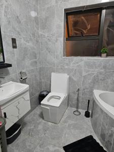 a bathroom with a white toilet and a sink at Cozy Corner Monavale in Harare