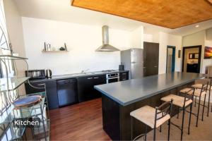 a kitchen with a large island with bar stools at Spacious Mt Hutt Ski & Summer Lodge in Methven with Spa in Methven +33 photos