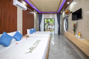 a hotel room with two beds and a tv at Hoi An Ocean Waves Homestay in Hà My Tây (2)