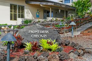 a sign that reads front desk check in on a rock at Paniolo Greens Resort in Waikoloa