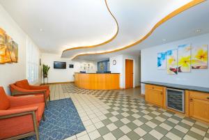 an office lobby with orange chairs and a kitchen at Paniolo Greens Resort in Waikoloa +25 photos
