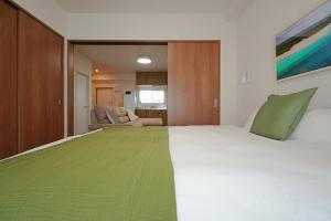 a bedroom with a large bed with a green blanket at INA HOUSE Miyakojima 302 in Miyakojima