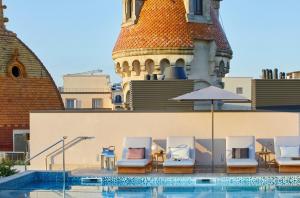 a group of chairs and an umbrella next to a pool at ME by Meliá Barcelona in Barcelona