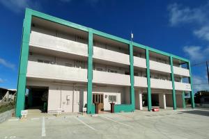 a large white building with green columns at INA HOUSE Miyakojima 302 in Miyakojima