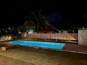 a swimming pool in front of a fence at night at Ploythai Villa 2 in Haad Pleayleam