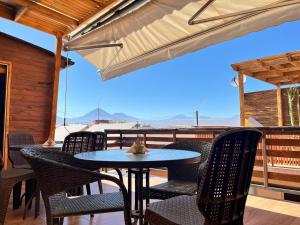 a patio with a table and chairs and an umbrella at Vicuña Lodge in San Pedro de Atacama