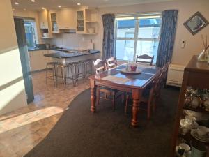 a kitchen and dining room with a wooden table and chairs at Rev it up Homestay in Feilding