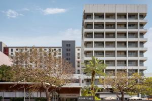 a tall white building with trees in front of it at Courtyard by Marriott Darwin in Darwin