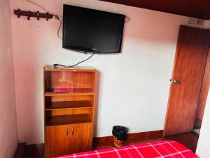 a bedroom with a tv on the wall and a book shelf at Nuevo Hotel Transportador in Bogotá