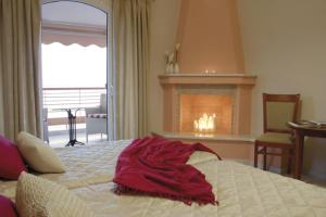 a red blanket on a bed in a room with a fireplace at Over Sea Rooms & Villas in Loutra Edipsou