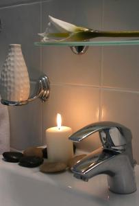 eine Kerze auf einem Waschbecken neben einem Wasserhahn. in der Unterkunft Over Sea Rooms & Villas in Loutra Edipsou