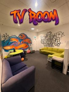 a room with a tv room with graffiti on the wall at Metro Adventurer Backpackers in Auckland