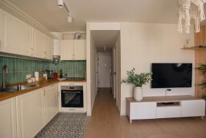 a kitchen with white cabinets and a tv on the wall at Alma de Mar in Finestrat
