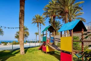 a playground with a slide and palm trees at SOL by Meliá Tenerife in Playa de las Americas