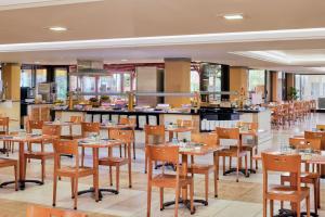 a restaurant with wooden tables and chairs and a kitchen at SOL by Meliá Tenerife in Playa de las Americas