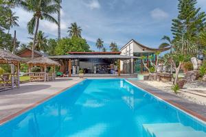 a large blue swimming pool in front of a house at Natai House Resort นาใต้เฮ้าส์ รีสอร์ท in Natai Beach