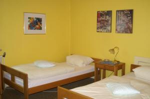 two beds in a room with yellow walls at Hotel Borcharding Rheine Mesum in Rheine