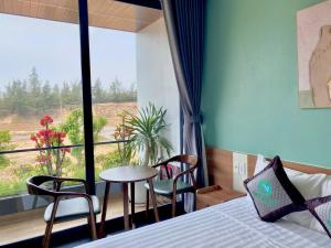 a bedroom with a bed and a window with a table and chairs at Homestay SkyLight in Dong Hoi