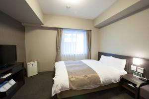 a hotel room with a bed and a television at Dormy Inn Kagoshima in Kagoshima