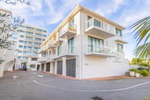 a white apartment building with a parking lot at Capri on Pilot Bay in Mount Maunganui +3 photos