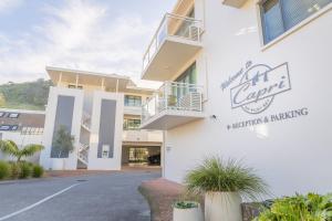 a white building with a sign on the side of it at Capri on Pilot Bay in Mount Maunganui