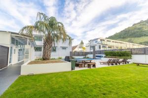 a view of the backyard of a house with a palm tree at Capri on Pilot Bay in Mount Maunganui