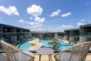 a balcony with two chairs and a swimming pool on a building at Elite Suites Villas Maikhao Phuket in Mai Khao Beach