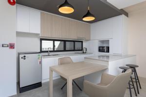 a kitchen with white cabinets and a wooden table and chairs at Elite Suites Villas Maikhao Phuket in Mai Khao Beach