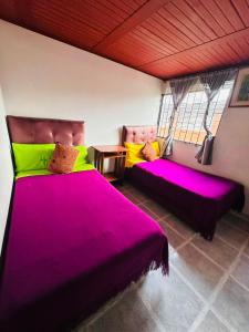a room with two beds with pink and yellow pillows at Nuevo Hotel Transportador in Bogotá
