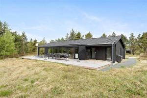 a black house with a deck in a field at 0410-Romo-Strandskaden-15 in Høm