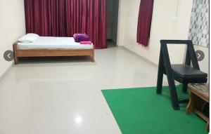 a room with a bed and a chair and a green rug at Hotel Alpha in Imphal International Airport