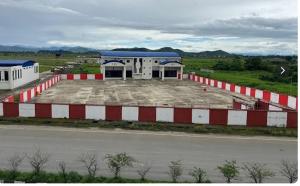 a red and white building with a parking lot at Hotel Alpha in Imphal International Airport