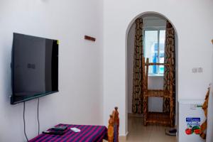 a living room with a flat screen tv on a wall at Visitors Inn Zanzibar in Jambiani