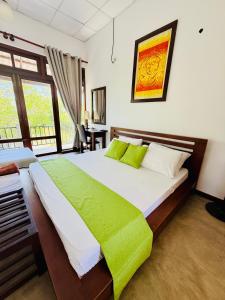 a bedroom with a large bed with a green blanket at Aurora Lagoon Front in Negombo