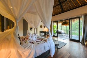 a bedroom with a white bed with a mosquito net at Villa Jasmine by Anakara in Ubud +7 photos