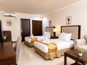 a hotel room with two beds and a couch at Plaza Hotel in Dili