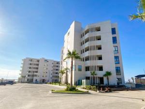 a large white building with palm trees in a parking lot at Wabi Sabi in Rosarito