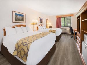 a hotel room with two beds and a desk at Baymont by Wyndham Hot Springs in Hot Springs +15 photos