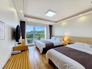 a hotel room with two beds and a television at Jeju Lavender Hotel in Seogwipo +28 photos