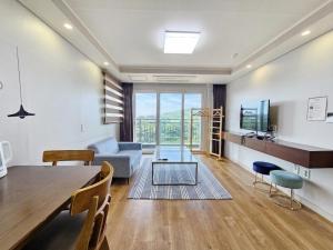 a living room with a table and a couch and a television at Jeju Lavender Hotel in Seogwipo