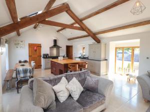 a living room with a gray couch and a kitchen at Wern Olau Cottage in Caernarfon