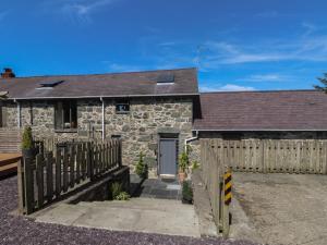 a stone house with a wooden fence and a gate at Wern Olau Cottage in Caernarfon