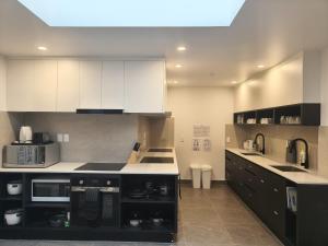 a kitchen with white cabinets and black appliances at Stay In Tekapo Backpackers in Lake Tekapo