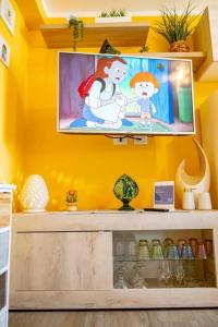 a room with a yellow wall with a tv on a shelf at Il Panoramico - Terrazza e Jacuzzi in Neviano