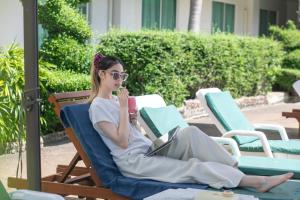 Eine Frau sitzt mit einem Laptop auf einem Stuhl. in der Unterkunft Windmill Resort Hotel Pattaya in Pattaya North