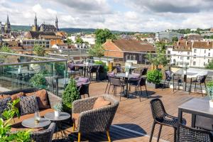 a balcony with tables and chairs and a view of a city at INNSiDE by Meliá Aachen in Aachen