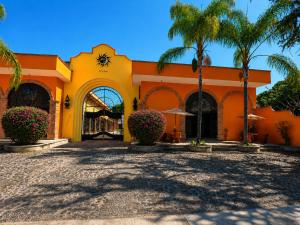 an orange building with palm trees and a courtyard at Hotel Boutique Sol y Luna SPA in Ajijic